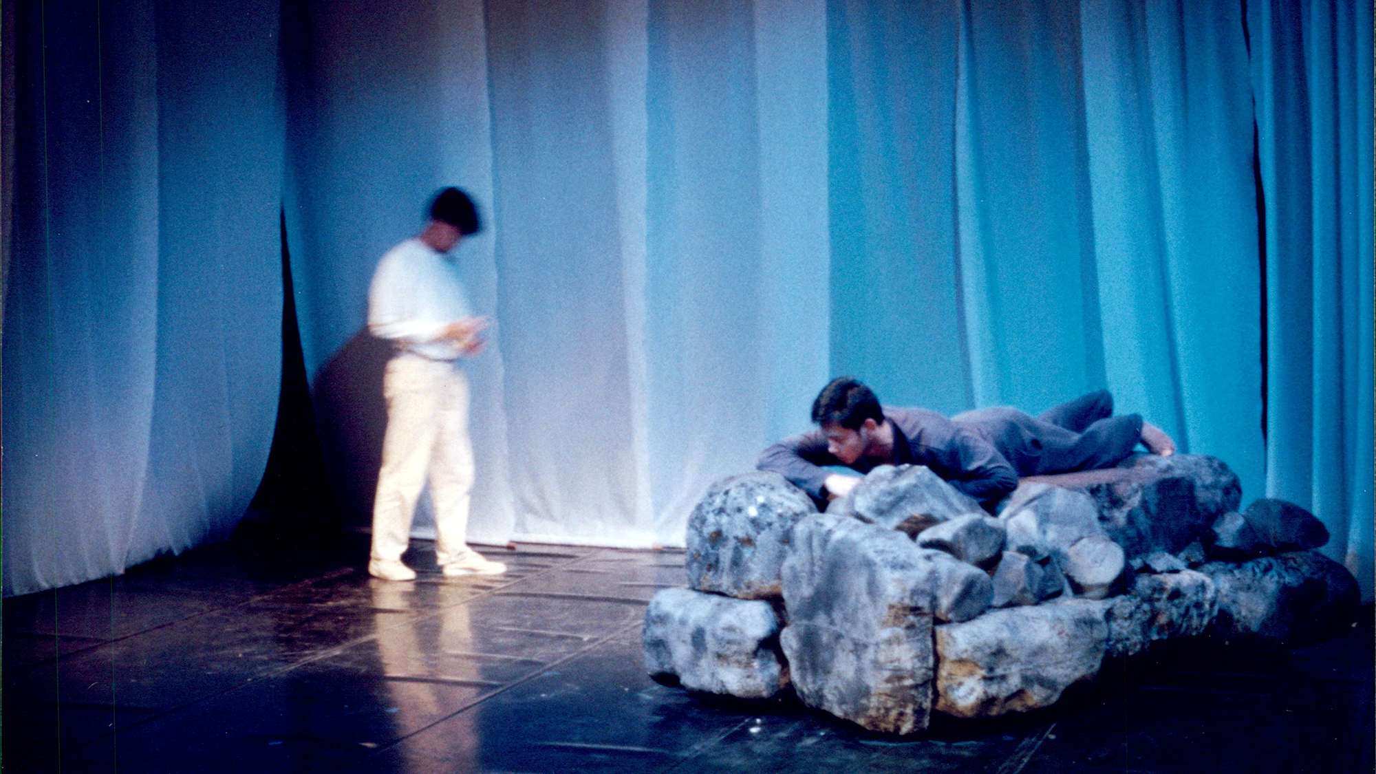Production still from Cetacea, a performer on a blue-lit stage.
