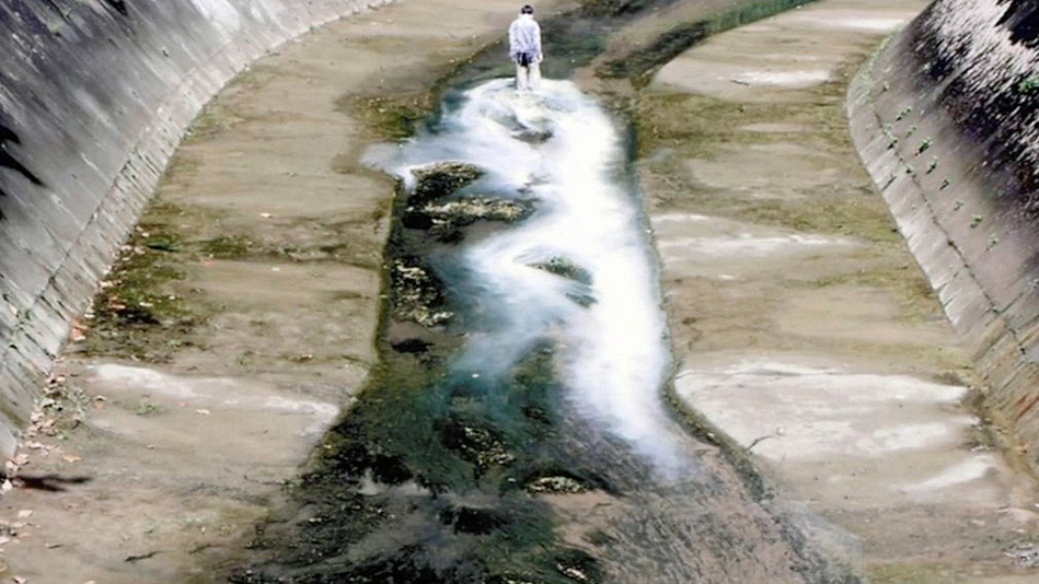 Still from All Lines Flow Out: a pale substance spreading through canal water.