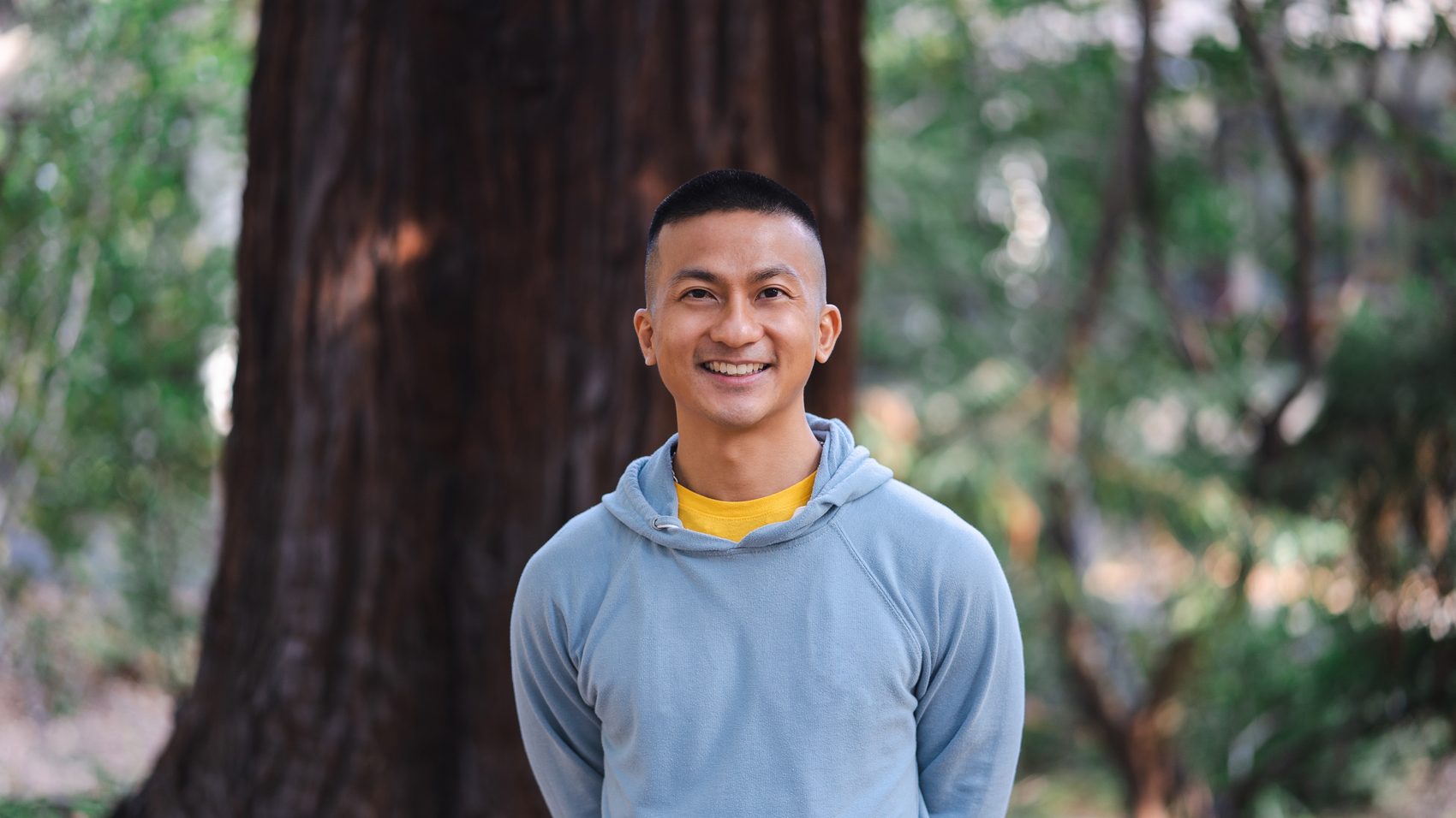 Portrait of Loo Zihan, standing before a redwood.